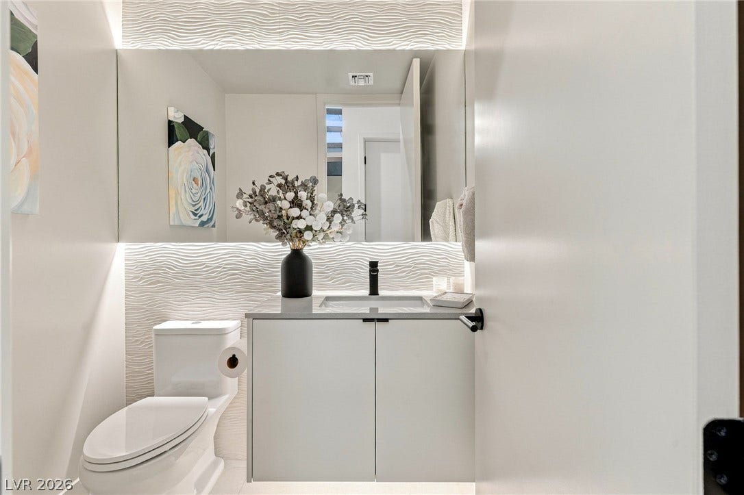 18 Heron Harbour Drive, Henderson, NV 89011 An elegant floating vanity pairs with a textured wall and integrated backlighting.