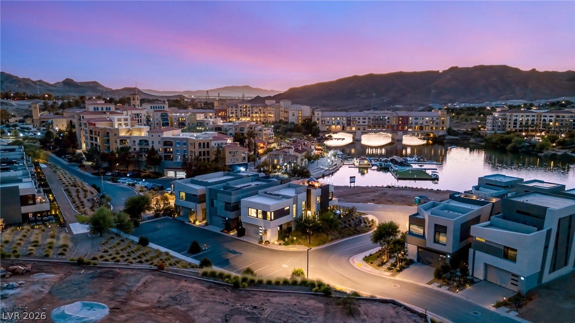 18 Heron Harbour Drive, Henderson, NV 89011 Dusk falls over a vibrant lakeside community nestled against a majestic mountain backdrop.