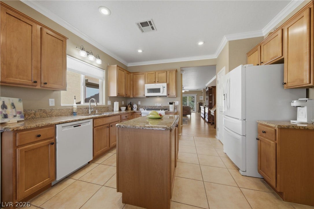 7340 Shelduck Street, North Las Vegas, NV 89084 Warm wood cabinetry and granite countertops frame a spacious kitchen with a central prep island.