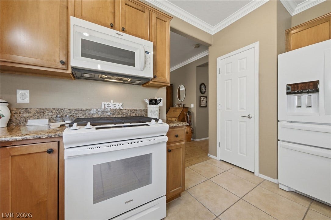 7340 Shelduck Street, North Las Vegas, NV 89084 Warm wood cabinetry and granite countertops frame a functional cooking area featuring tile flooring.