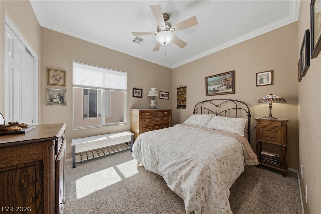 7340 Shelduck Street, North Las Vegas, NV 89084 High ceilings decorated with elegant crown molding elevate this carpeted bedroom.