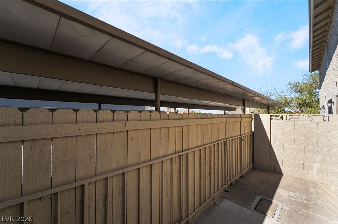 535 Sellers Place, Henderson, NV 89011 A covered parking structure sits adjacent to a private concrete patio bordered by fencing.
