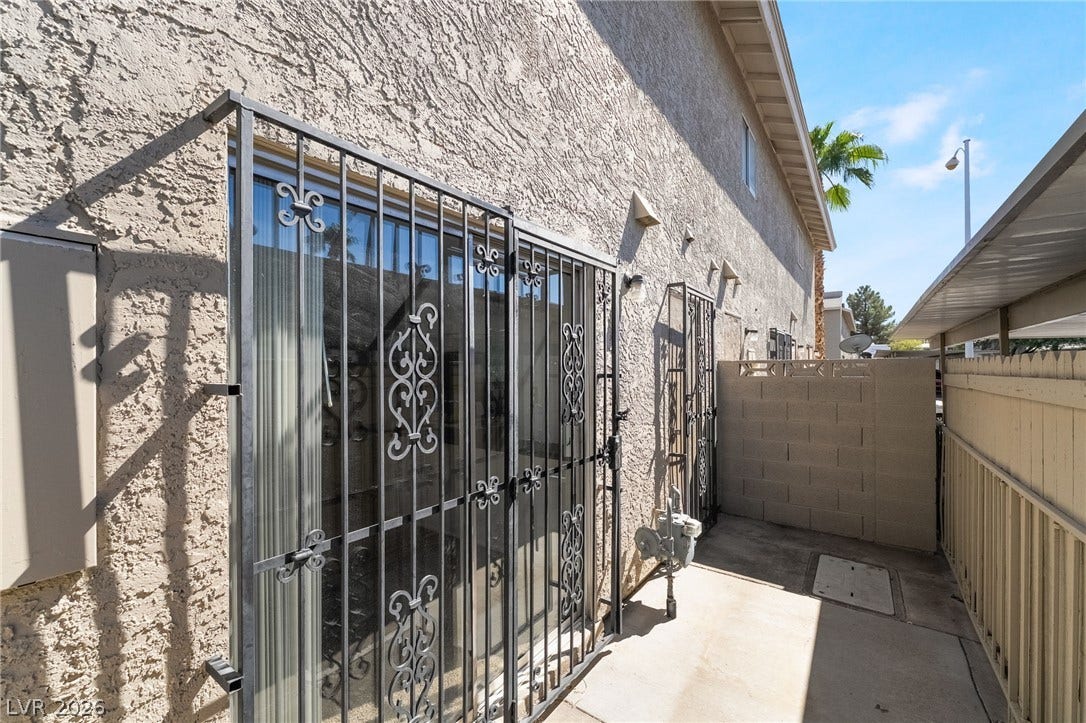535 Sellers Place, Henderson, NV 89011 A narrow side pathway borders the textured stucco exterior wall lined with secured sliding glass doors.