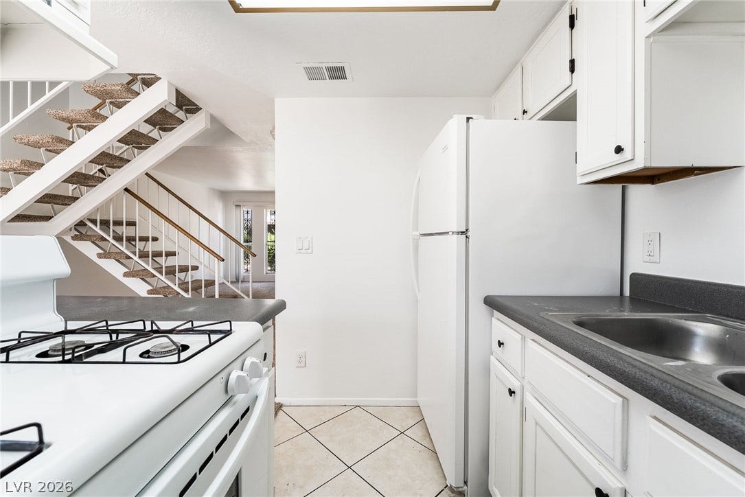 535 Sellers Place, Henderson, NV 89011 Tile flooring and durable countertops define this functional kitchen adjacent to carpeted stairs.