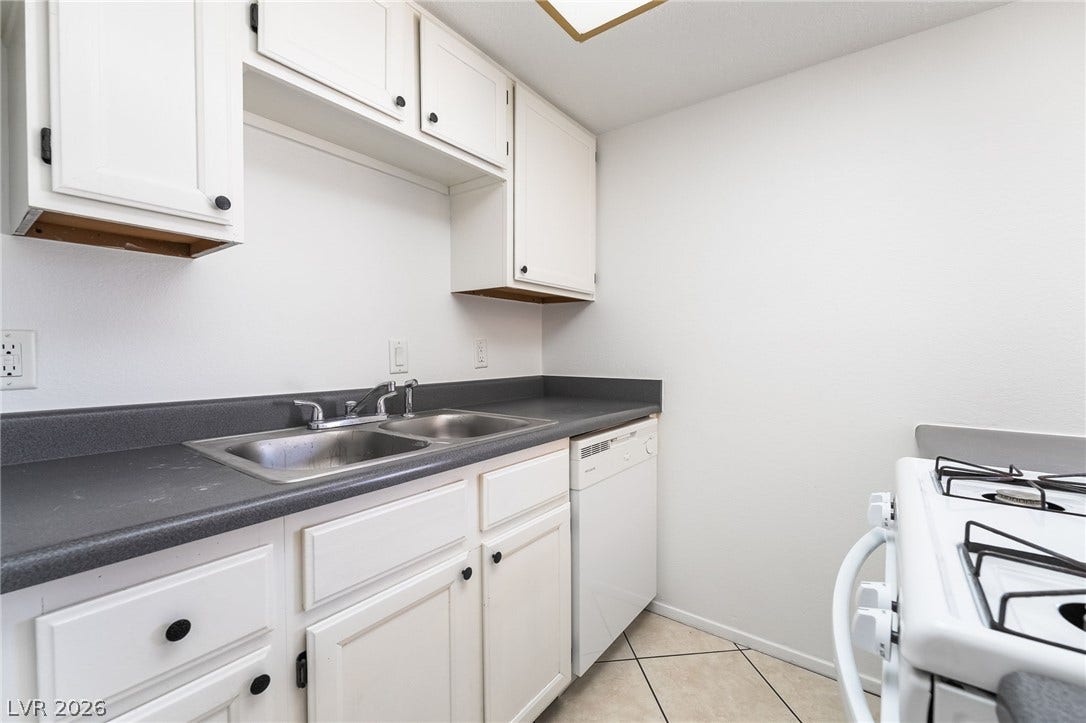 535 Sellers Place, Henderson, NV 89011 A functional kitchen space highlights clean white cabinetry and classic tiled flooring.