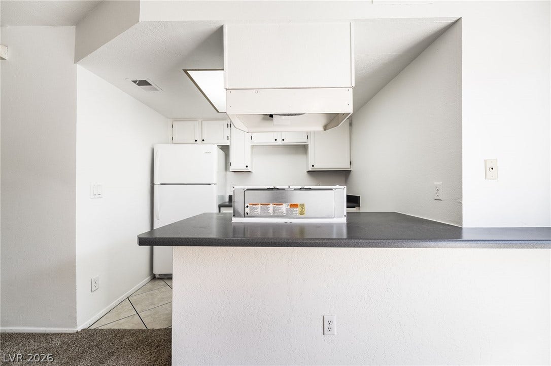 535 Sellers Place, Henderson, NV 89011 Dark countertops provide a striking contrast against white cabinetry in this functional kitchen layout.