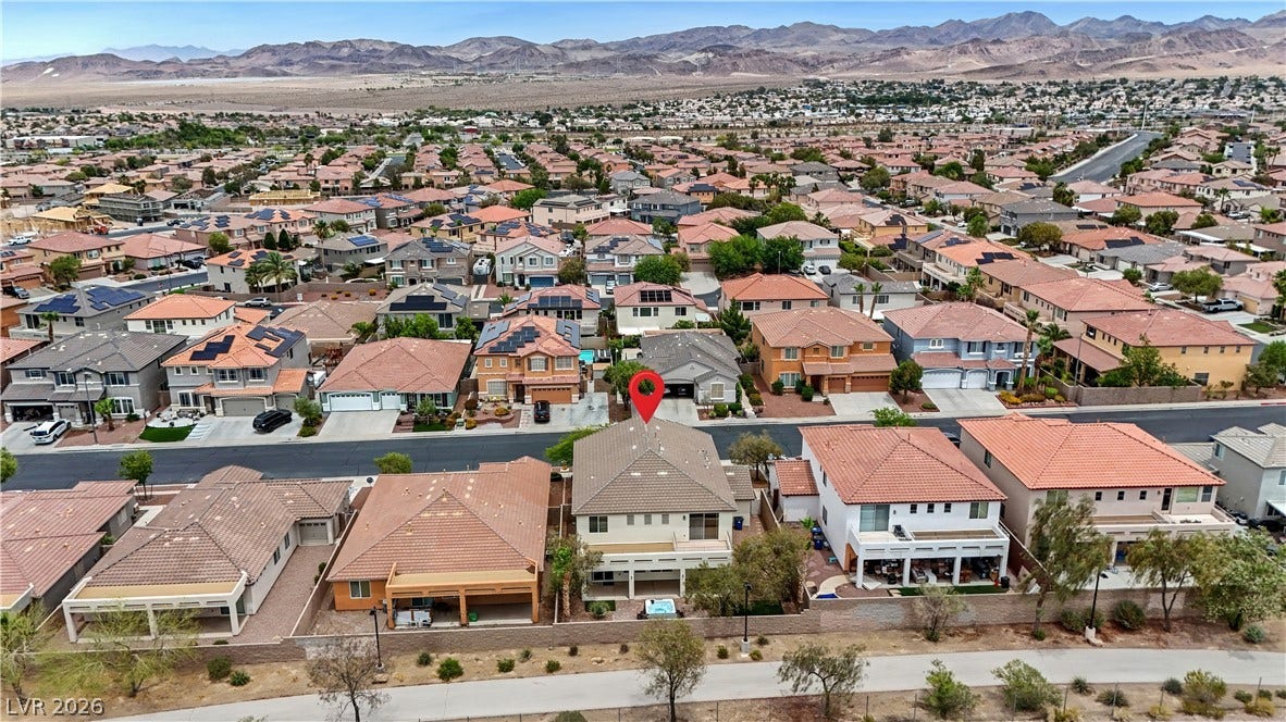 625 Bighorn Creek Street, Henderson, NV 89002 An aerial perspective reveals a vibrant neighborhood with diverse rooflines and distant mountain vistas.