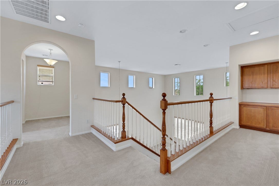 625 Bighorn Creek Street, Henderson, NV 89002 A well-lit landing with recessed lighting, an arched doorway, and built-in wooden cabinetry offers comfortable upstairs living.