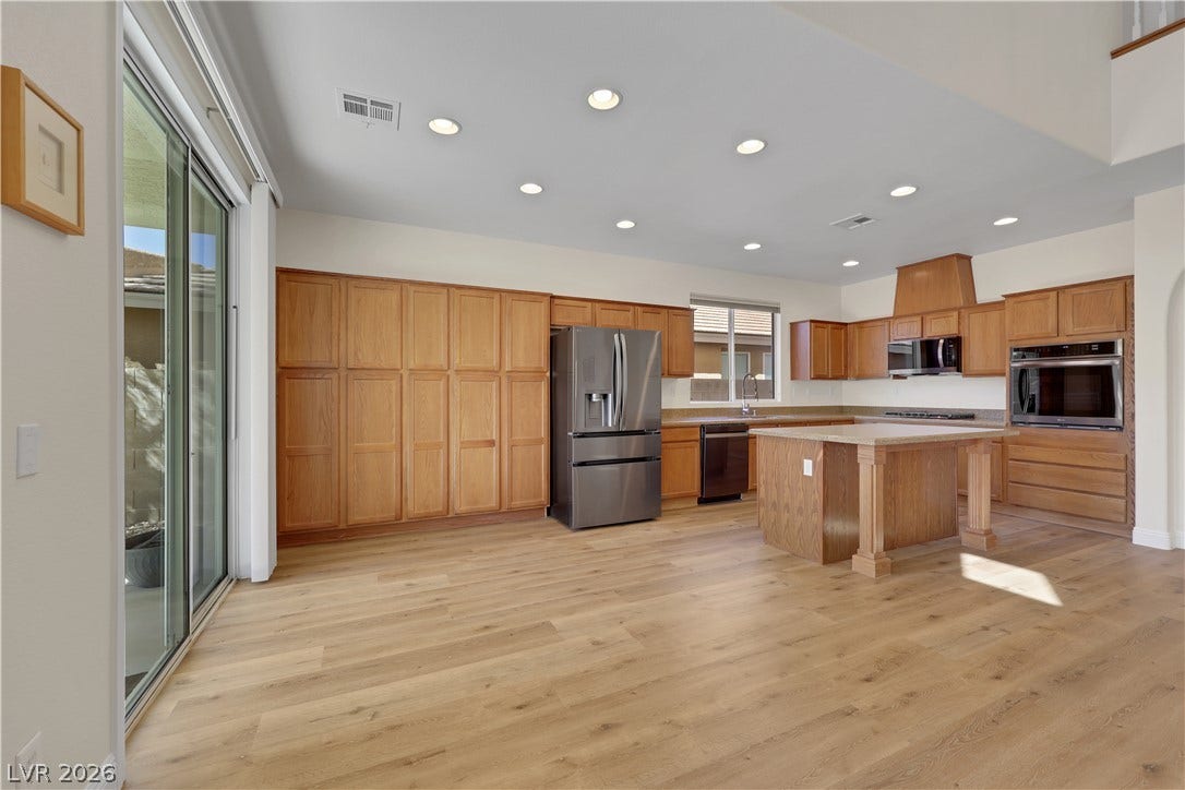 625 Bighorn Creek Street, Henderson, NV 89002 Warm wood cabinetry and wood flooring anchor this spacious, well-lit kitchen area.