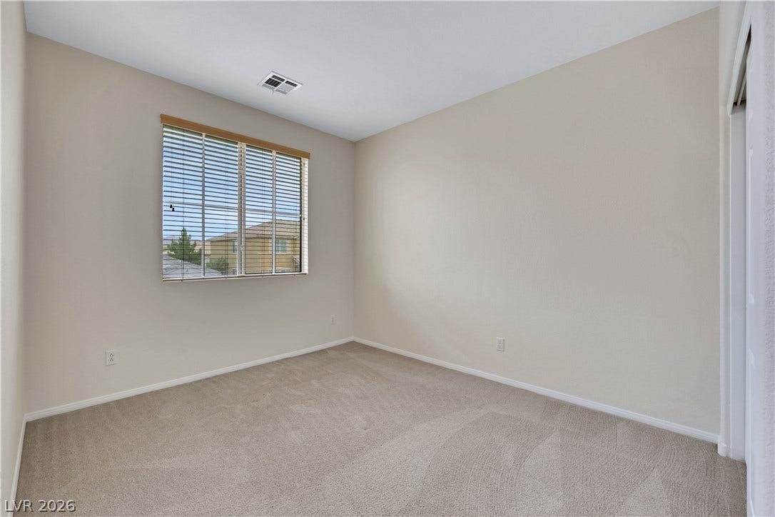 625 Bighorn Creek Street, Henderson, NV 89002 A neutral-toned room ready for personalization, featuring soft carpeting and natural light.