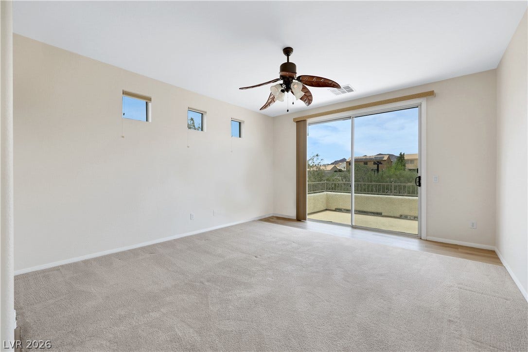 625 Bighorn Creek Street, Henderson, NV 89002 A spacious room with a sliding glass door opening to an outdoor balcony and a ceiling fan for comfort.