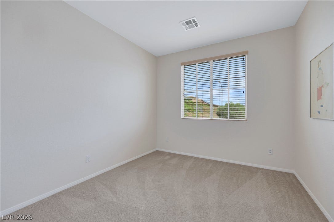 625 Bighorn Creek Street, Henderson, NV 89002 A well-lit bedroom features plush carpeting and ample natural light from a window with blinds.