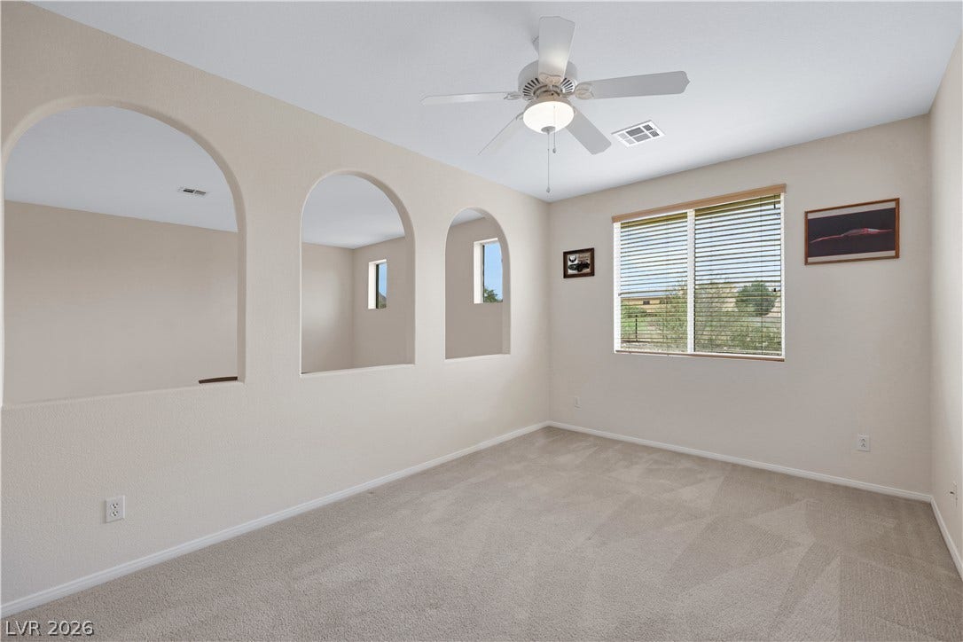 625 Bighorn Creek Street, Henderson, NV 89002 Arched wall openings and a window framing outdoor greenery define this spacious room.