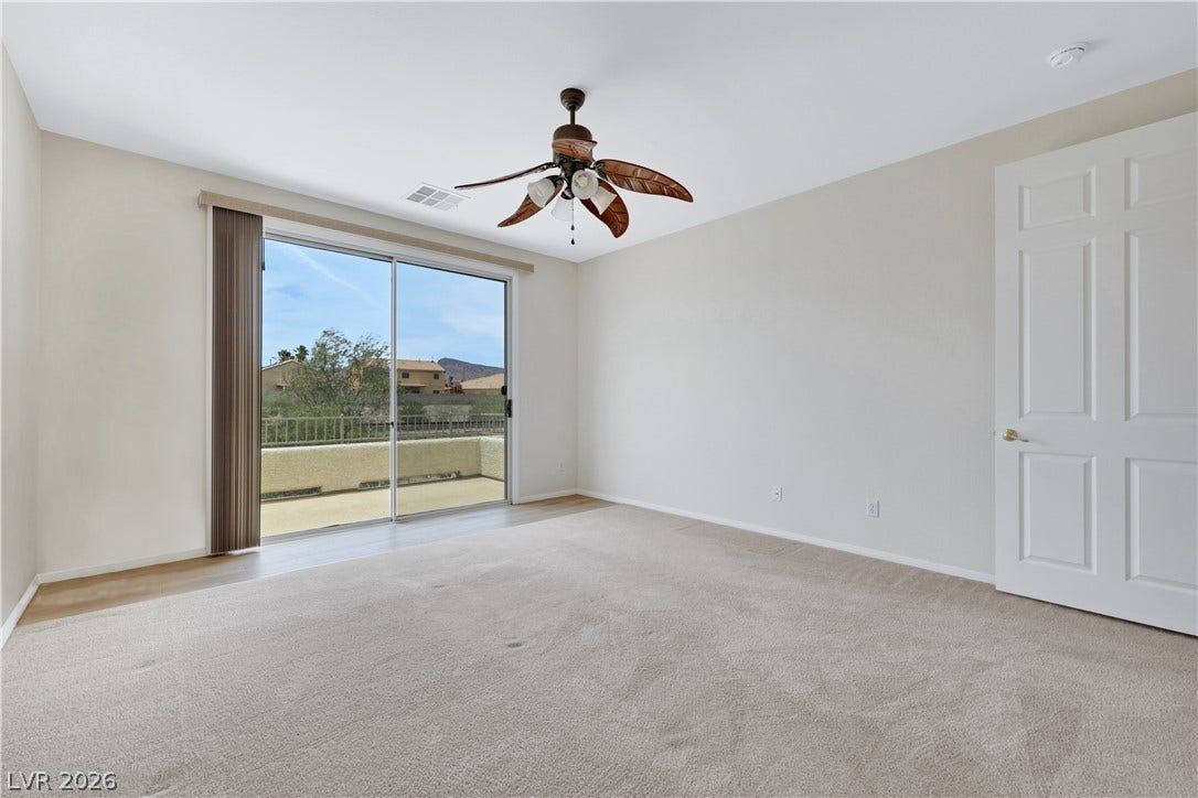 625 Bighorn Creek Street, Henderson, NV 89002 A spacious bedroom provides direct access to an outdoor balcony, offering scenic views.
