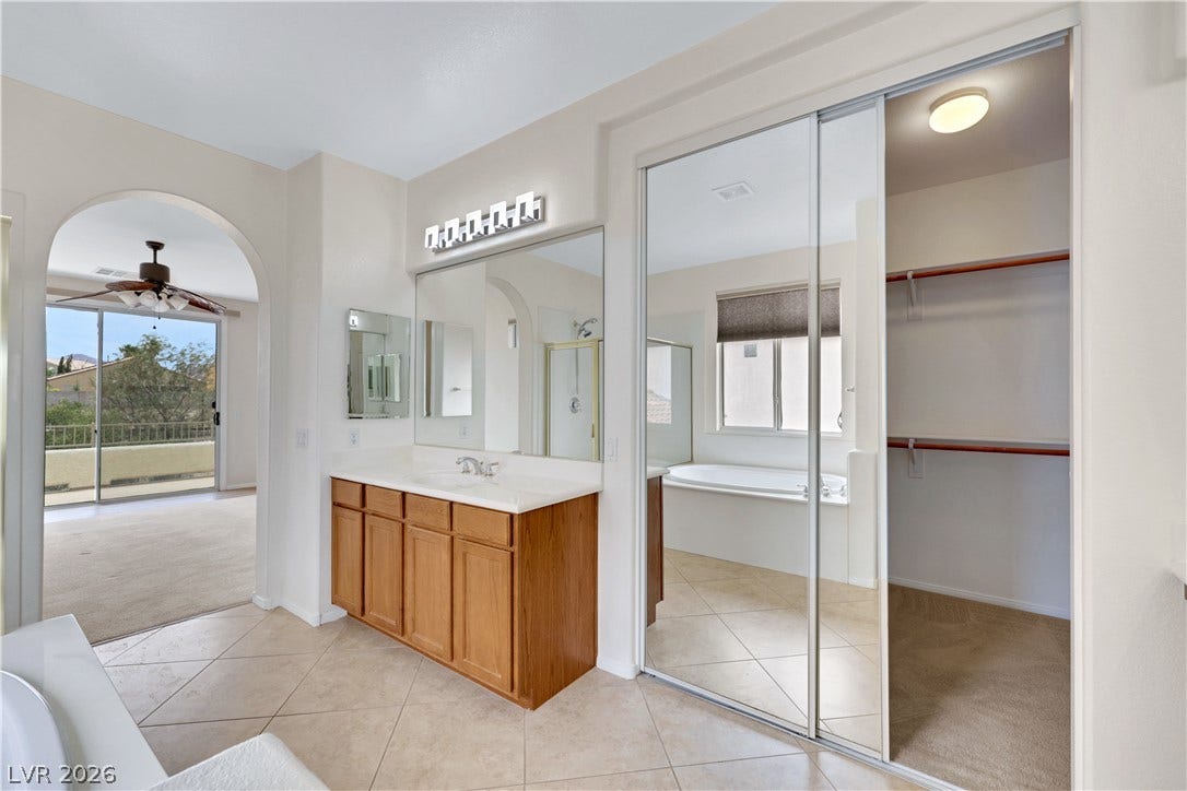 625 Bighorn Creek Street, Henderson, NV 89002 A well-lit primary bathroom featuring a spacious vanity, walk-in closet, and a private tub area with exterior access.