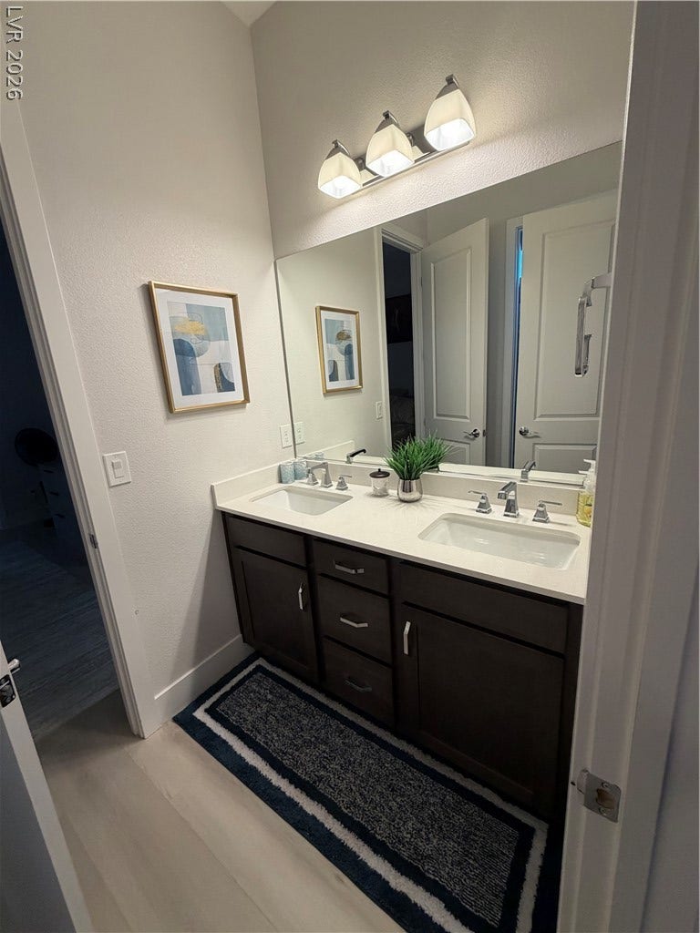 11725 Hatchling Avenue, Las Vegas, NV 89138 A modern double vanity bathroom featuring dark cabinetry paired with sleek quartz countertops in this jack and jill bathroom.