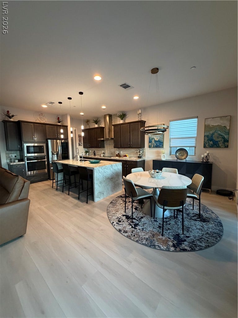 11725 Hatchling Avenue, Las Vegas, NV 89138 Gleaming light luxuy vinyl flooring unites a modern kitchen and dining area under 10 ft high ceilings.
