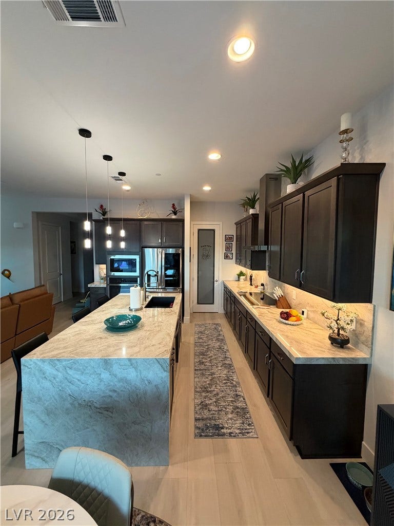 11725 Hatchling Avenue, Las Vegas, NV 89138 Rich dark cabinetry beautifully contrasts with the elegant waterfall island countertops in this modern kitchen.