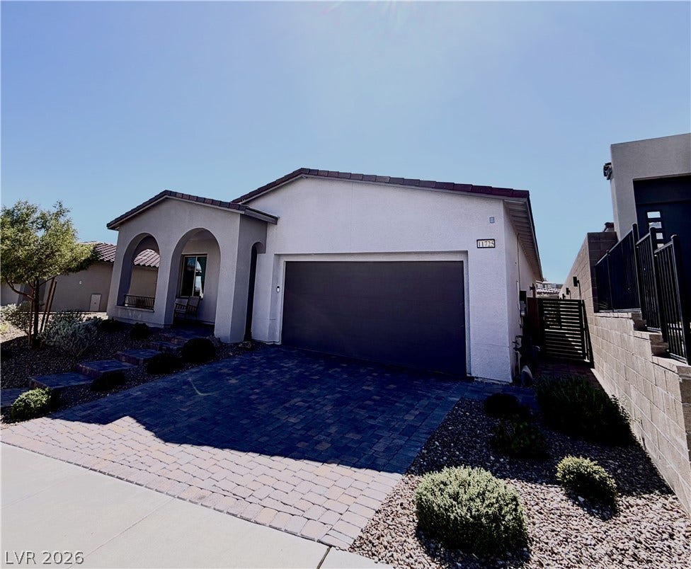 11725 Hatchling Avenue, Las Vegas, NV 89138 A paved driveway leads to a modern single-level residence with classic arched entryways.