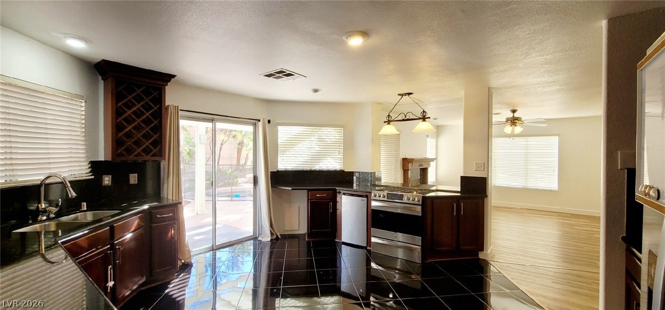 2001 Silverton Drive, Henderson, NV 89074 Gleaming tile floors and rich cabinetry define this modern kitchen with seamless outdoor access.