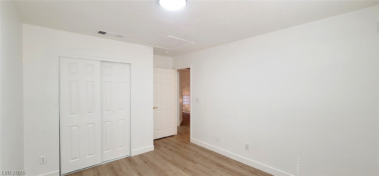 2001 Silverton Drive, Henderson, NV 89074 Warm wood-style flooring and clean white walls create a serene, minimalist bedroom space.