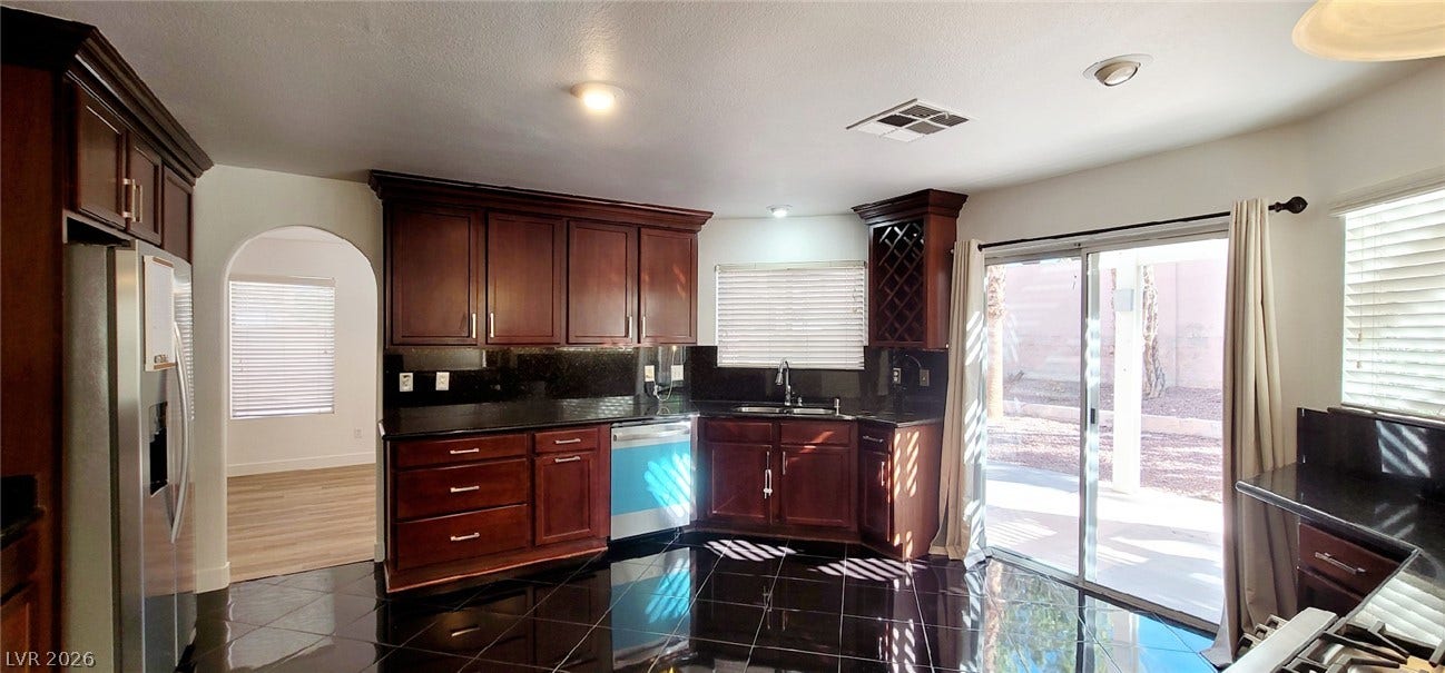 2001 Silverton Drive, Henderson, NV 89074 Polished tile flooring and rich wood cabinetry define this kitchen space with patio access.