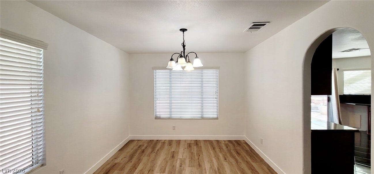 2001 Silverton Drive, Henderson, NV 89074 An arched doorway leads to the kitchen from this light-filled dining space featuring wood floors.
