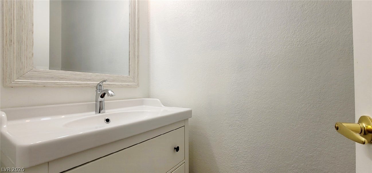 2001 Silverton Drive, Henderson, NV 89074 An elegant framed mirror hangs above a classic white vanity sink in this clean powder room.