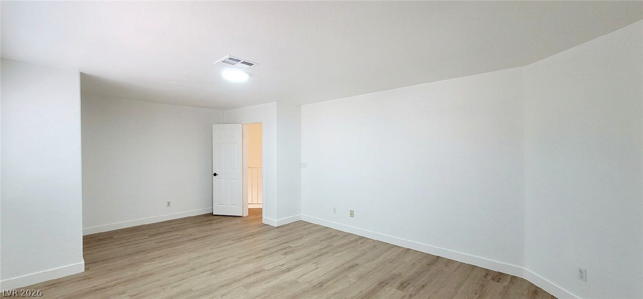 2001 Silverton Drive, Henderson, NV 89074 Smooth wood-style flooring runs through this airy, light-filled bedroom with pristine white walls.