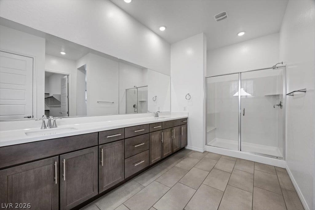 A spacious vanity with double sinks anchors this modern primary bathroom featuring a large walk in  shower.