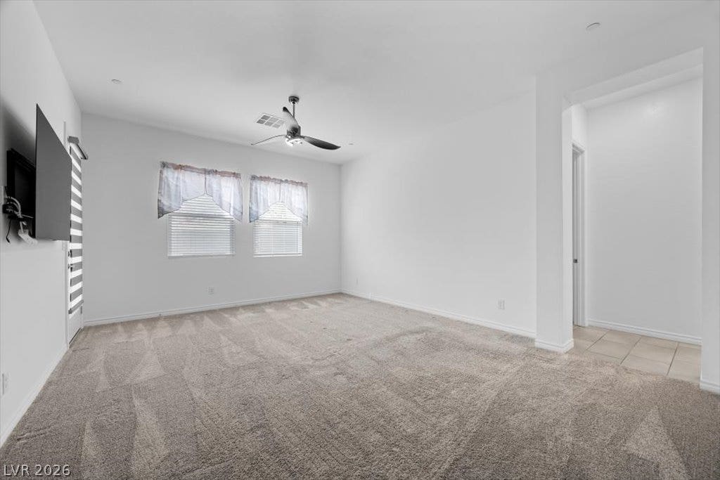 An open spacious primary bedroom features plush neutral carpeting and nice windows and access to patio.