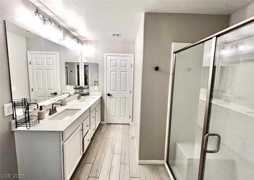 6483 Perch Coo Avenue, Las Vegas, NV 89130 Clean lines and a spacious dual vanity define this modern, well-appointed primary bathroom.