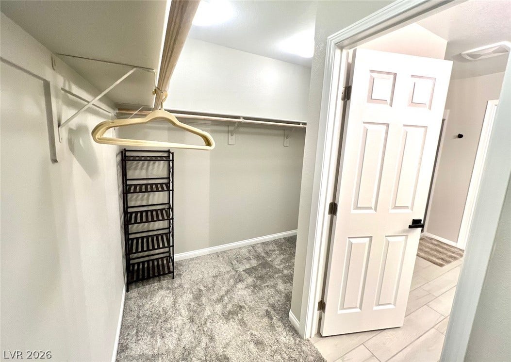 6483 Perch Coo Avenue, Las Vegas, NV 89130 Ample storage options define this functional walk-in closet featuring plush carpeting and built-in shelving.