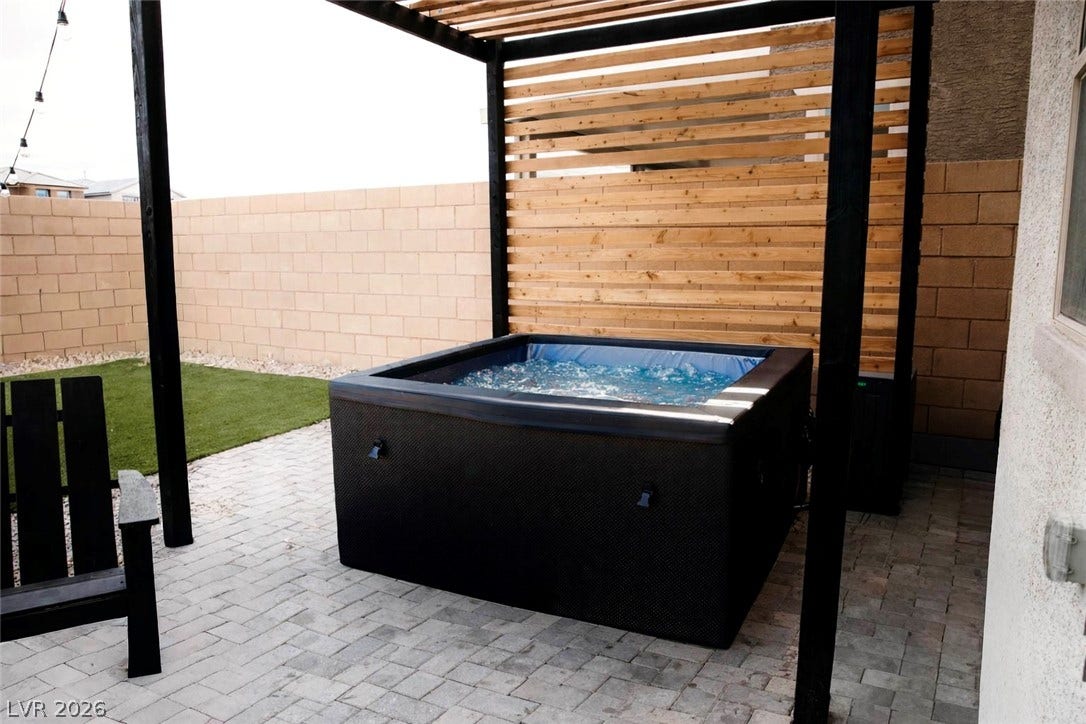 6483 Perch Coo Avenue, Las Vegas, NV 89130 An inviting backyard retreat highlights a modern spa nestled beneath a custom wooden pergola structure.
