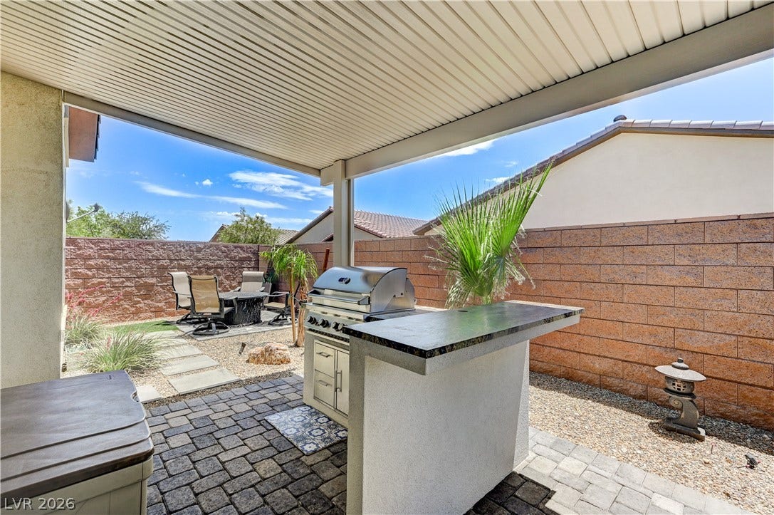 3605 Greenbriar Bluff Avenue, North Las Vegas, NV 89081 A covered patio with paved flooring features an outdoor kitchen area and a block-walled yard.