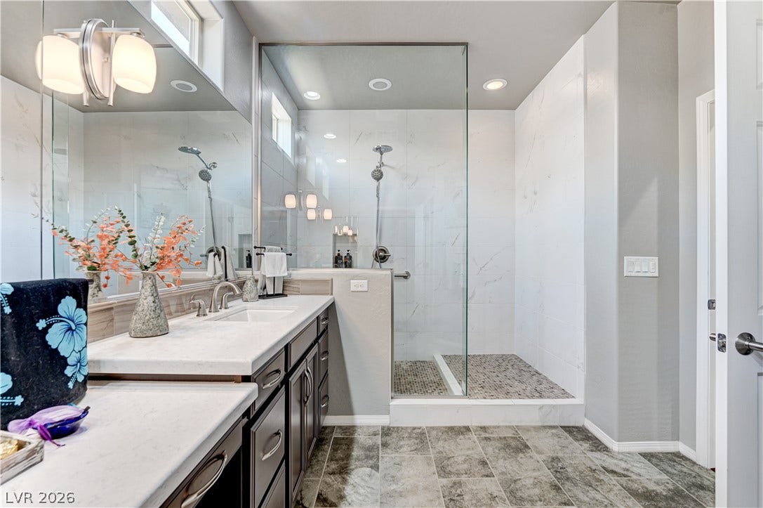 3605 Greenbriar Bluff Avenue, North Las Vegas, NV 89081 A modern bathroom features a glass-enclosed shower, stone counters, and durable tile flooring.