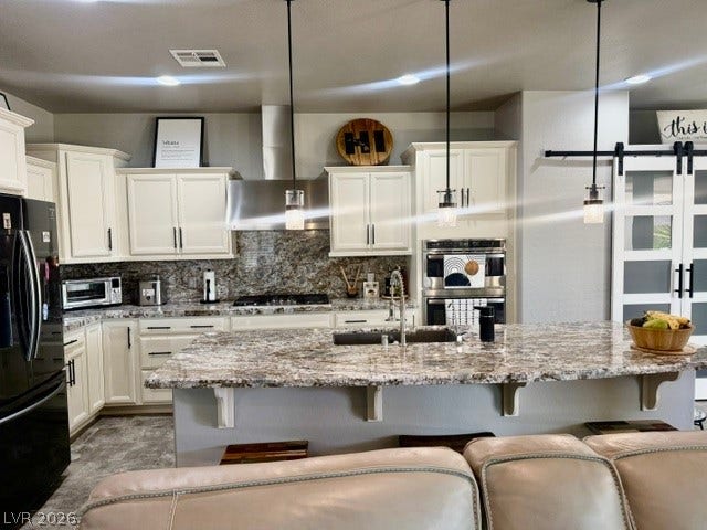 3605 Greenbriar Bluff Avenue, North Las Vegas, NV 89081 An expansive granite island centers this modern kitchen featuring white cabinetry and built-in stainless appliances.
