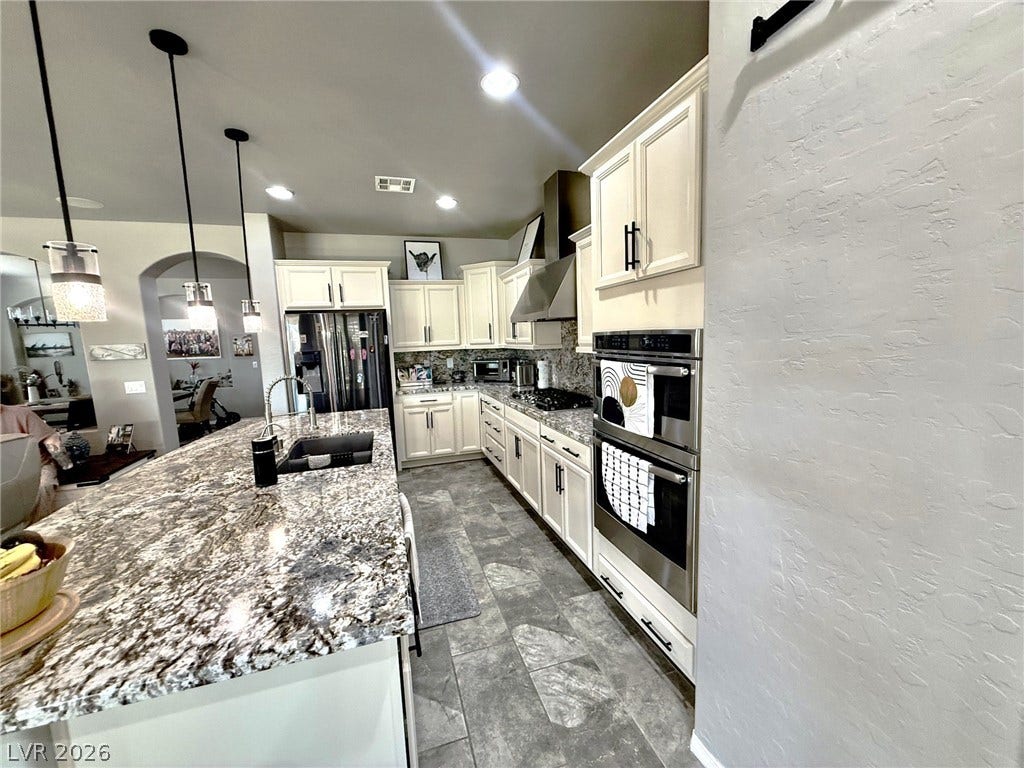 3605 Greenbriar Bluff Avenue, North Las Vegas, NV 89081 Gleaming stone countertops and stainless appliances anchor this spacious culinary space with custom tile floors.