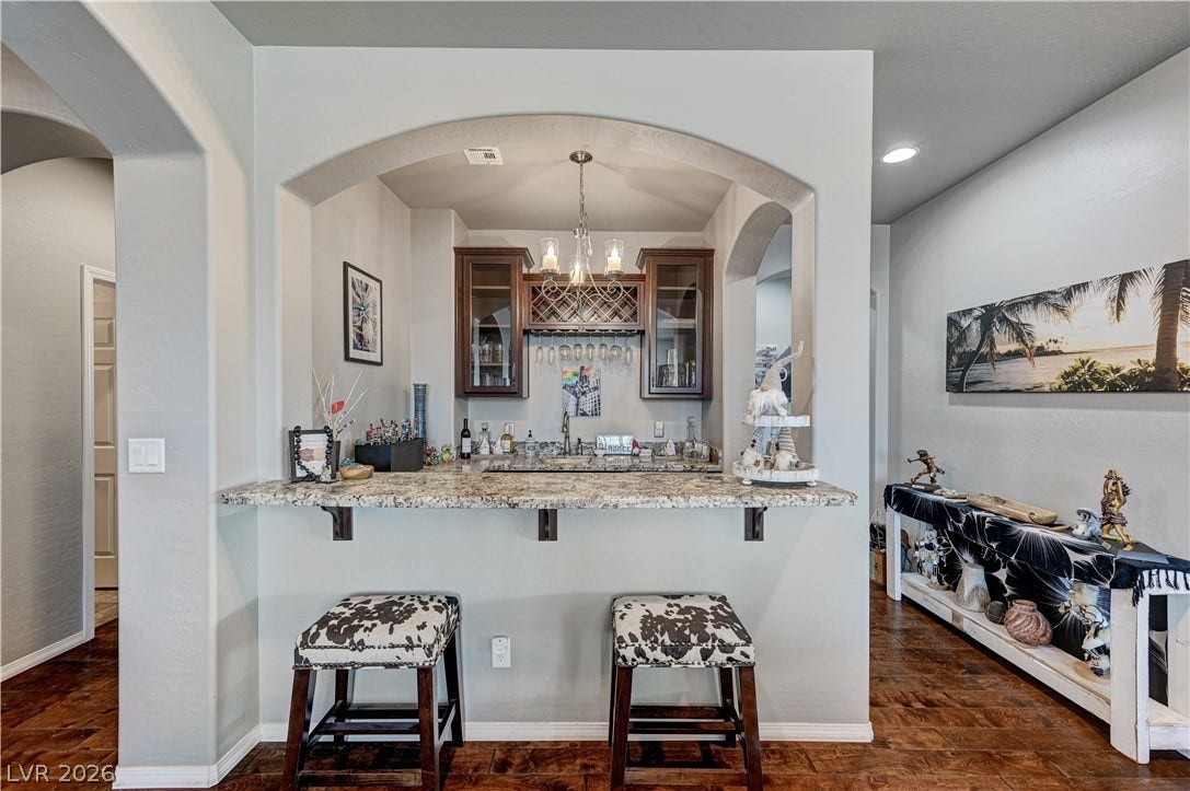 3605 Greenbriar Bluff Avenue, North Las Vegas, NV 89081 An elegant arched wet bar offers granite countertops, custom cabinetry, and rich hardwood flooring.