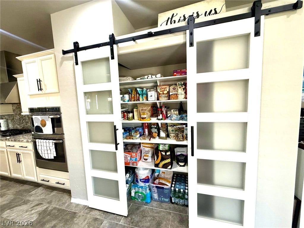3605 Greenbriar Bluff Avenue, North Las Vegas, NV 89081 Double sliding barn doors open to reveal an organized pantry with built-in shelving.