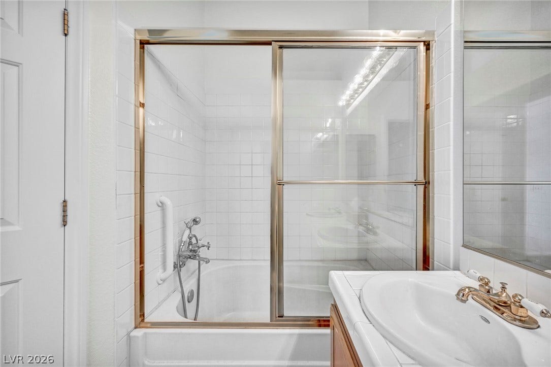 1745 Lily Pond Circle, Henderson, NV 89012 Crisp white wall tile wraps the tub and shower enclosure beside a classic vanity.