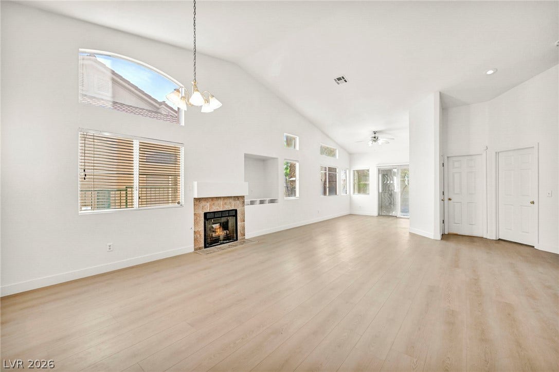 1745 Lily Pond Circle, Henderson, NV 89012 A spacious living room features soaring vaulted ceilings, wood-look flooring, and a stone-faced fireplace.