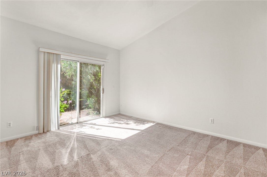 1745 Lily Pond Circle, Henderson, NV 89012 Sliding glass doors open to garden views from this bedroom featuring vaulted ceilings.