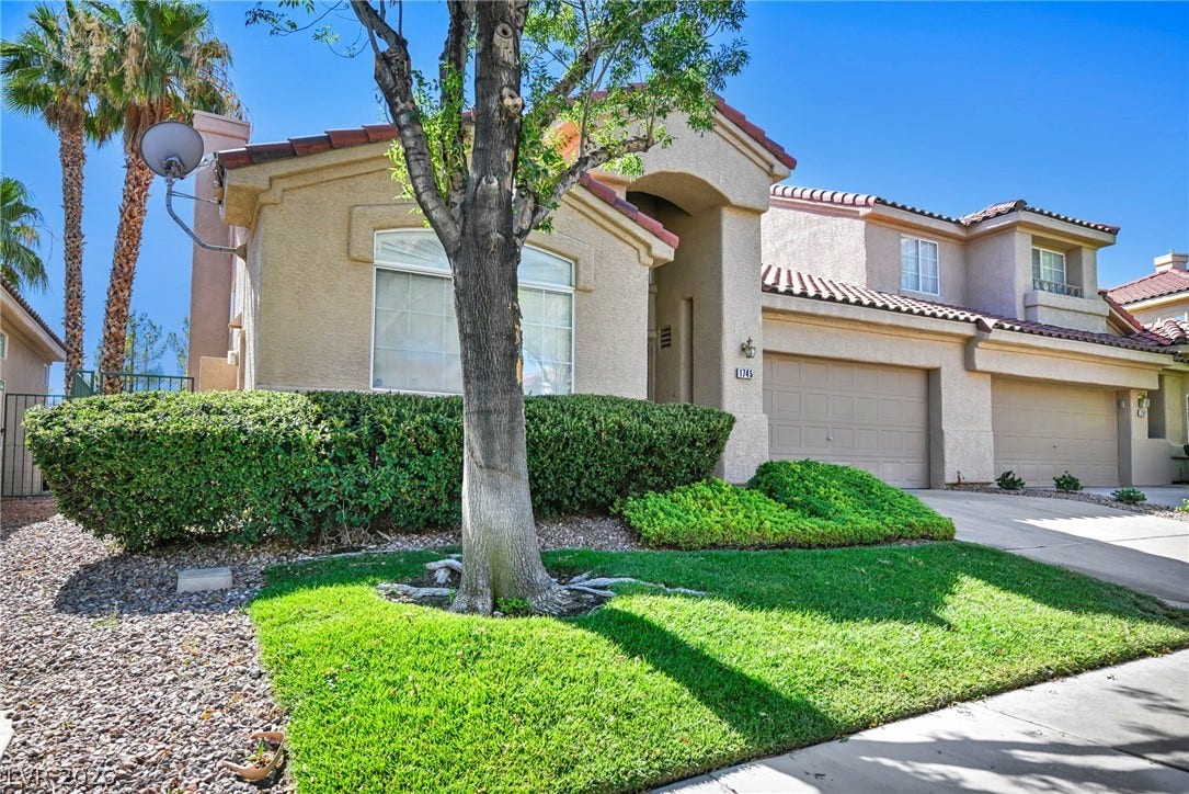 1745 Lily Pond Circle, Henderson, NV 89012 Manicured green lawn and mature trees frame the classic stucco facade of this welcoming residence.