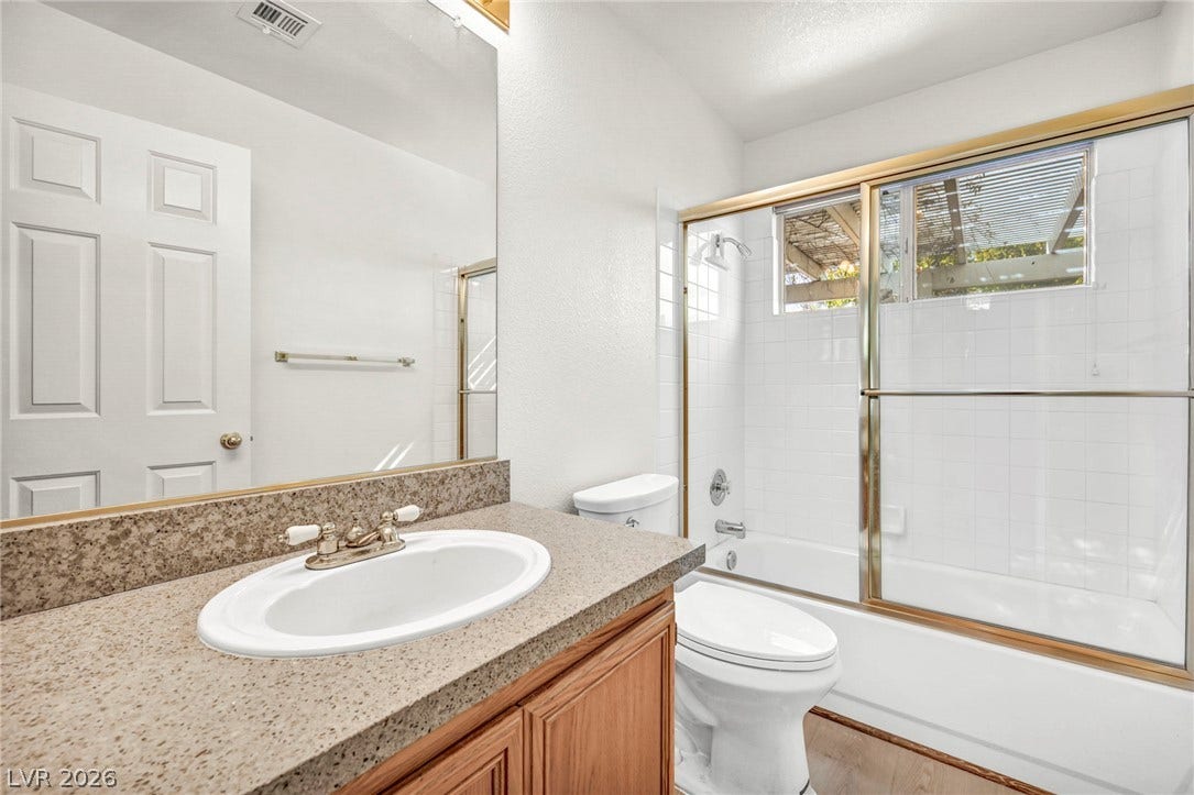 1745 Lily Pond Circle, Henderson, NV 89012 A well-maintained bathroom highlights a stone-look vanity countertop alongside a classic tub and shower combination.