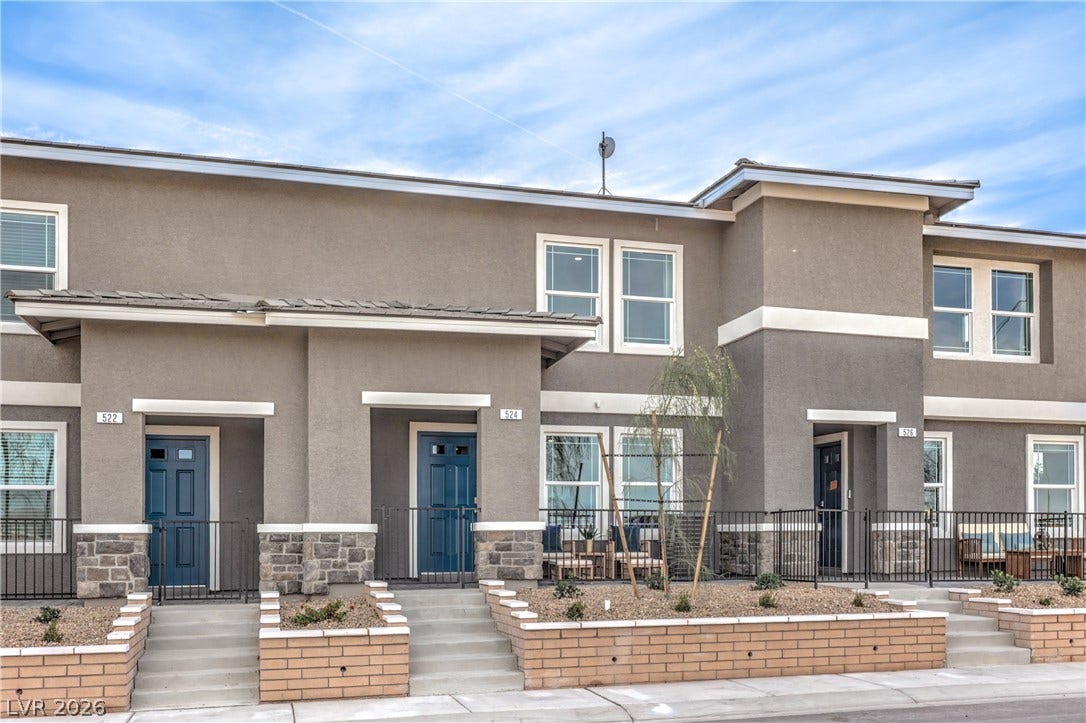 A modern multi-family exterior displays sleek stucco walls complemented by stone and brick accents.