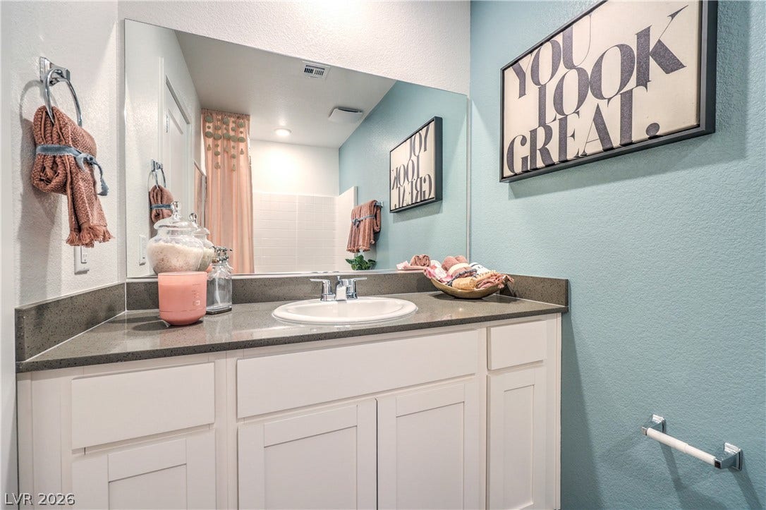 Smooth stone countertops pair with clean white cabinetry in this modern bathroom setup.
