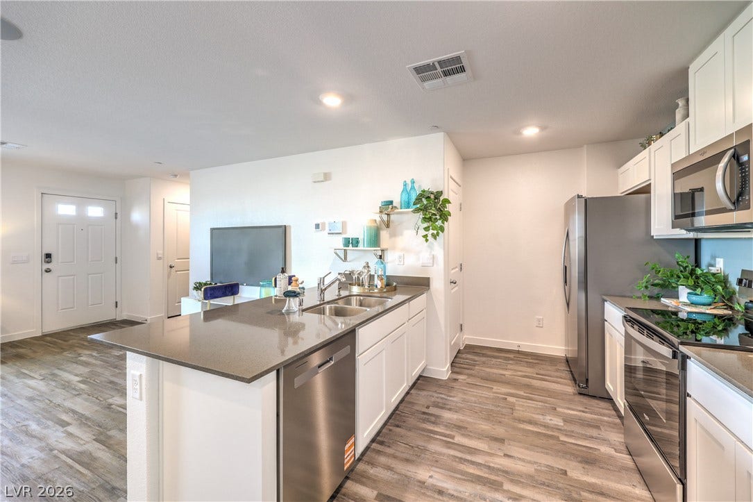 Gleaming stone countertops and wood-look flooring anchor this airy, open-concept cooking space.