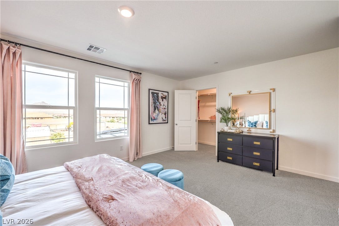 Plentiful natural light streams through multiple windows highlighting carpeted flooring and a walk-in closet.