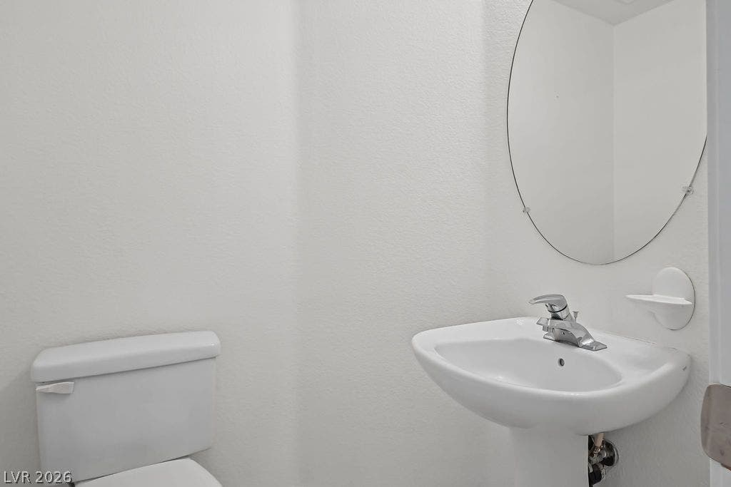 754 Solitude Point Avenue, Henderson, NV 89012 A classic pedestal sink paired with an oval mirror anchors this crisp half bath.